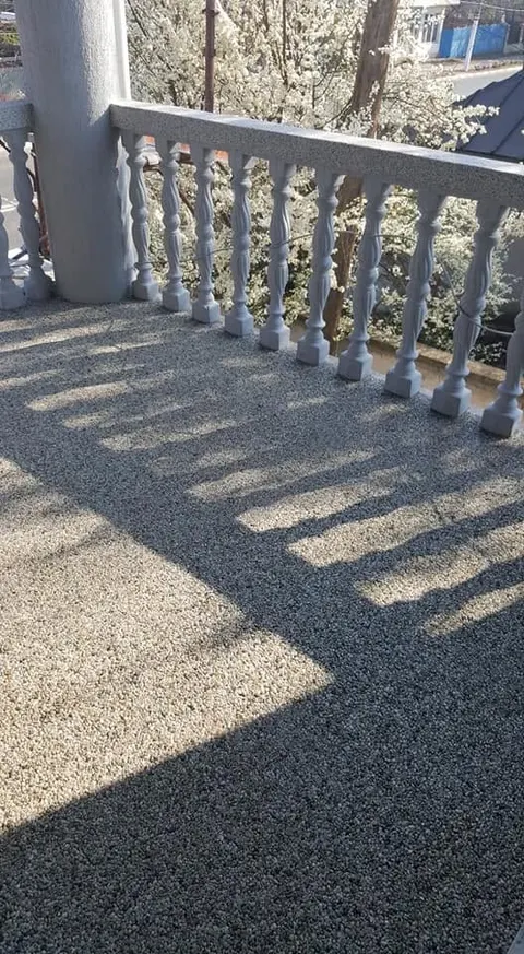 Terasă din covor de piatră gri cu umbrele unei balustrade clasice din beton