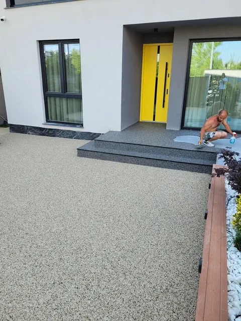 Terasă crem cu trepte antracit la o casă modernă cu ușă galbenă